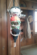 Four baseball caps stacked vertically inside a white macrame' hanging net. 