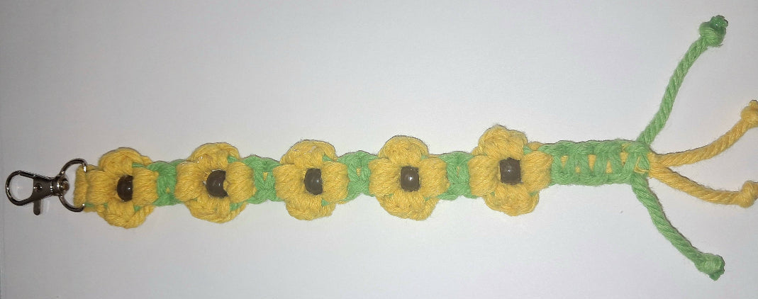 A hand-crafted Macrame Daisy sunflower keychain or bag charm with a metal lobster clasp at the top, displayed against a plain white background.