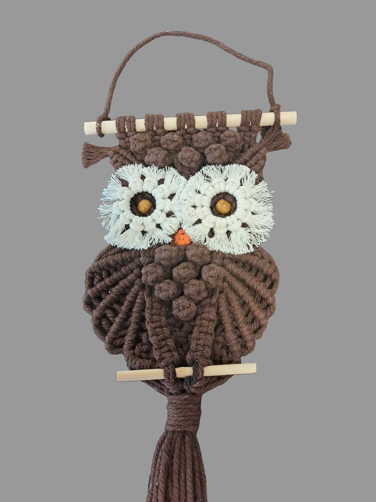 Handmade macrame owl on gray background. 